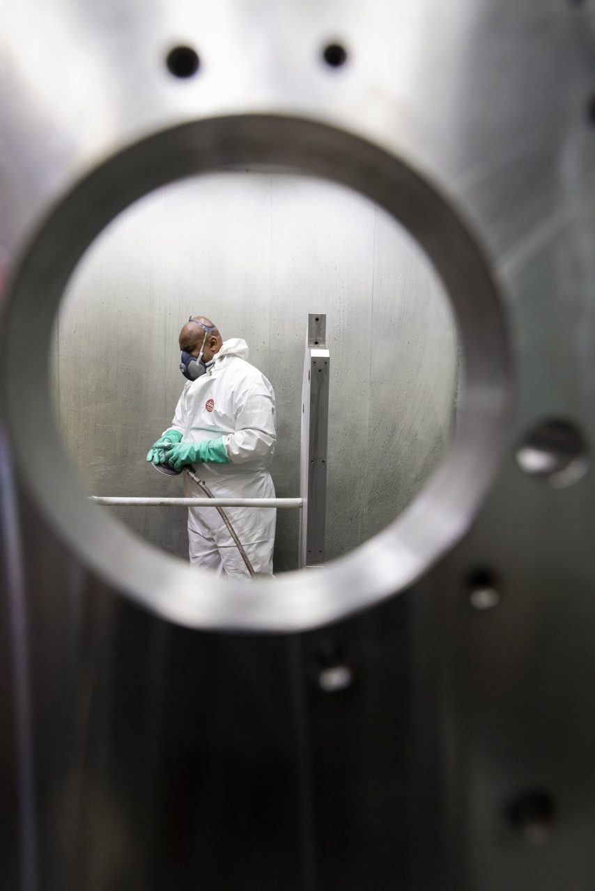 Photo industrielle d'un ouvrier au travail dans une cabine de ponçage.