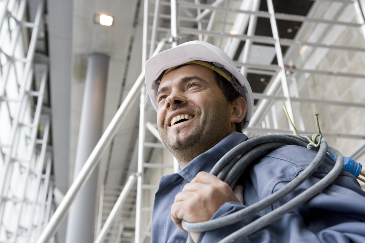 Portrait métier d'un électricien souriant sur un chantier BTP