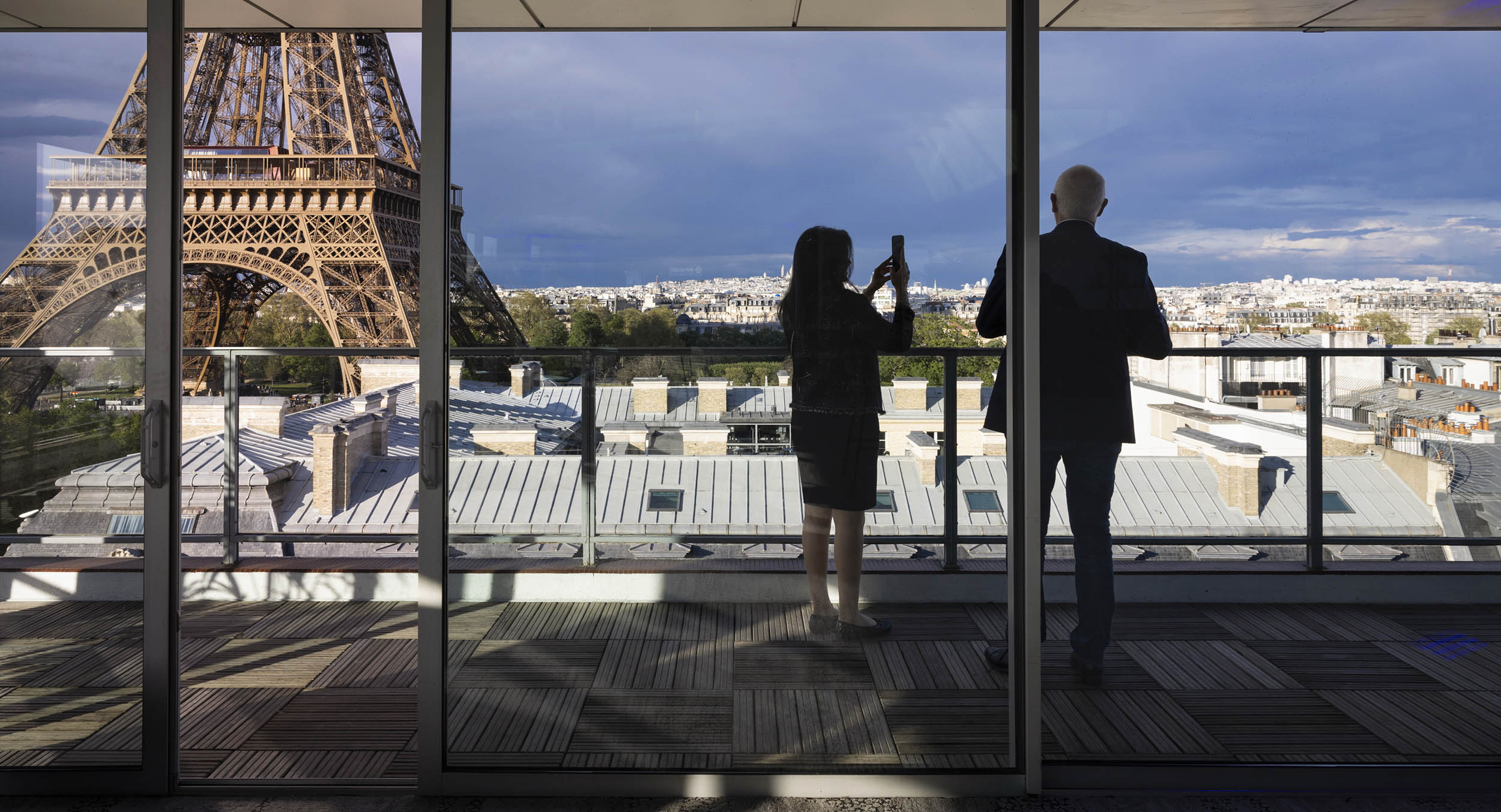 Photographe événementiel à Paris : deux invités sur une terrasse avec vue panoramique sur la Tour Eiffel lors d'une réception corporate internationale